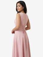 Woman wearing a pink dress with a bow detail on a beige background