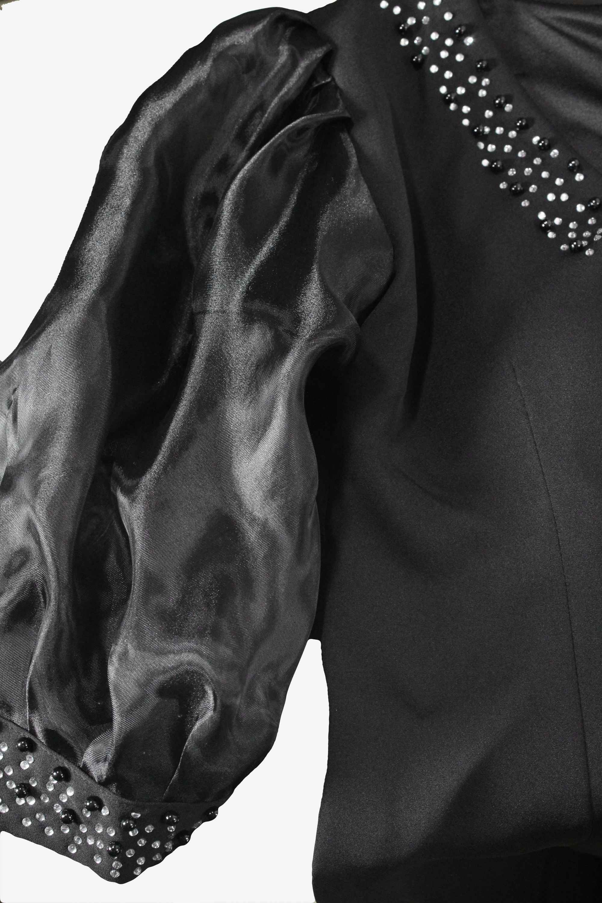 Black satin garment with embellished trim on a white background