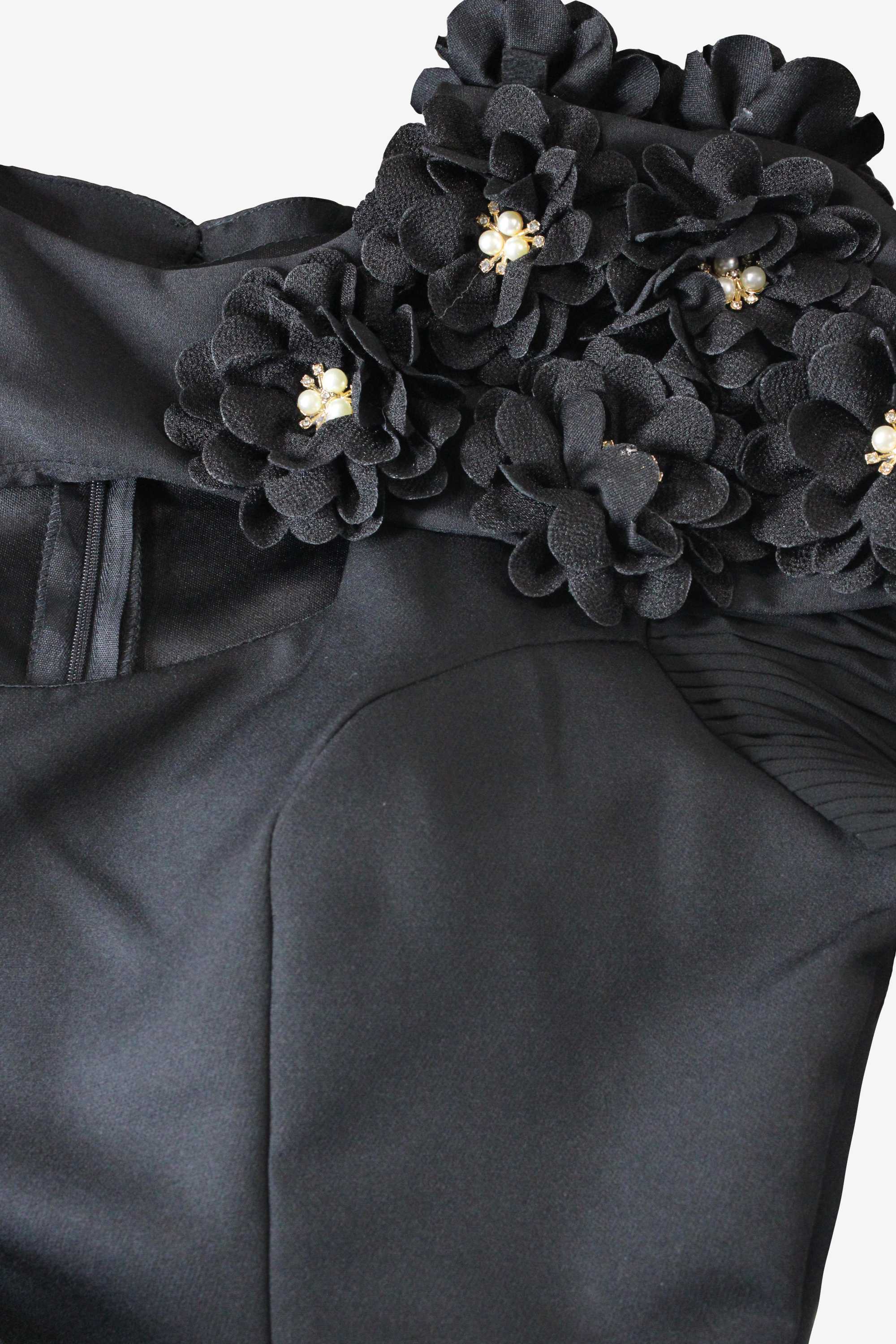Black floral shoulder detail on a garment with gold accents.