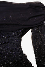 Close-up of a black dress with beaded detailing on a white background