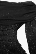 Close-up of a black dress with sparkling details on a white background