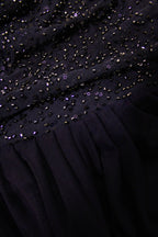 Close-up of a black dress with bead embellishments on a dark background