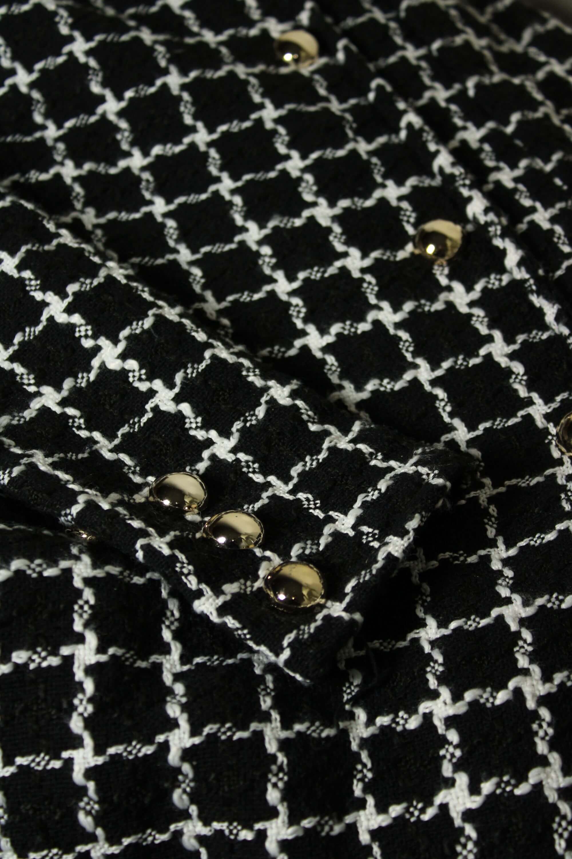 Close-up of a black and white checkered fabric with metallic buttons.