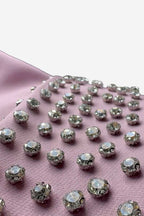 Silver rhinestone stones on a pink fabric background