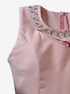 Pink top with embellished neckline on a light pink background