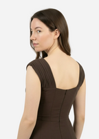 Woman wearing a brown dress with a plain white background